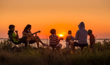 people sitting on the beach with campfire at sunsetの写真素材