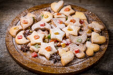 Holiday cookies with icing and sweet candied fruit on wooden dish at the tableの写真素材