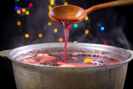 Wooden spoon stir mulled wine preparing in metal kettleの写真素材
