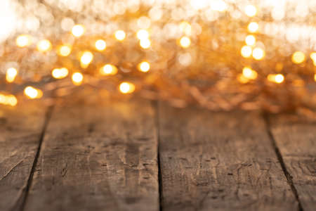 wooden background with electric garland lamp - festive blurred christmas decoration with empty copy spaceの写真素材