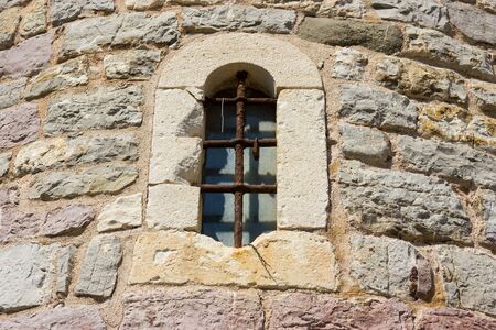Ancient window with cell in the stone wall.の写真素材