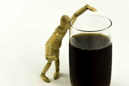 Wooden doll trying to have a drinkの写真素材
