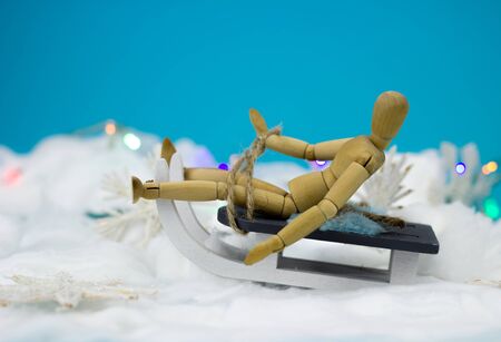 Wooden man on a sleigh on blue background