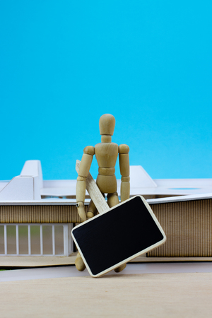 Wooden man with sign in front of miniature buildingの写真素材