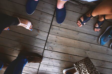 People in shoes stand on a wooden floor from boards, top view