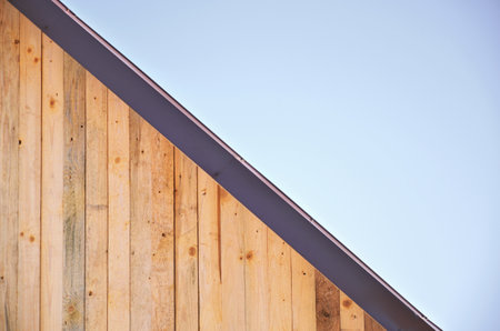 Wooden roof of light boards covered with metal against the blue sky in the afternoon