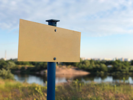 Blank metal signboard, warning shield on the background of nature and lake in the eveningの写真素材