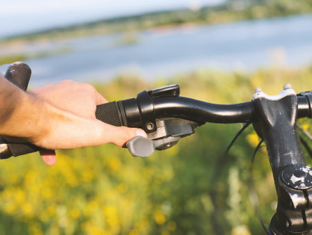 A young guy holds a bike on the background of a summer sunny meadow and lake close-upの写真素材