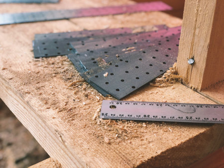 Metal connecting plates for rafter beams and a ruler lying on a tree and in sawdust in focus close-upの写真素材