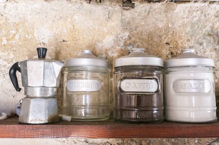 Old coffee pot on a shelf with cans of coffee, sugar and salt.