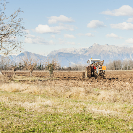 Agricultural landscape. With tractor plowing a field. The mountains in the background.の写真素材