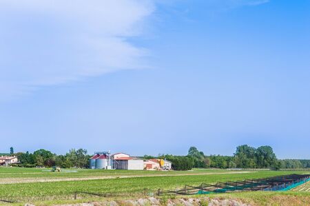 Agricultural landscape with farm silos and tractorの写真素材