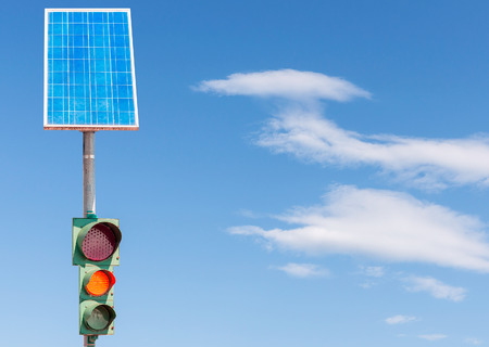 Road traffic light powered by electricity generated from a solar panel. Blue skyの写真素材