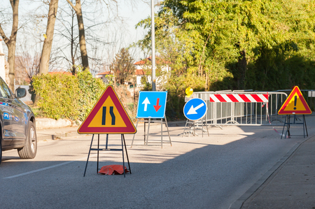 Road sign lane narrowing. In the background, blurred a roadworks site.の写真素材