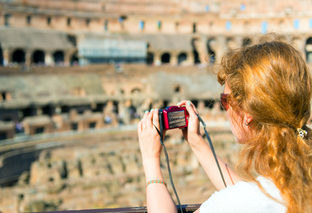 Young female tourist takes a picture inside the Coliseum in Rome, Italy
