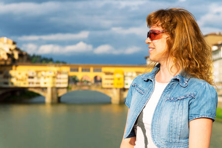 Young female tourist on the background of the Ponte Vecchio in Florence, Italyの写真素材