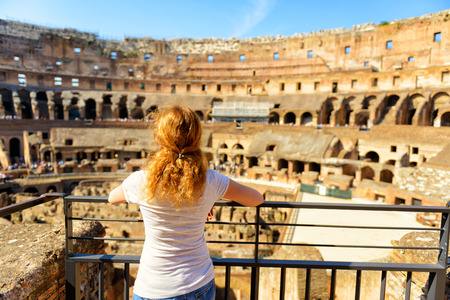 The golden-haired female tourist looks at the Colosseum in Rome, Italy. The Colosseum is an important monument of antiquity and is one of the main tourist attractions of Rome.の写真素材