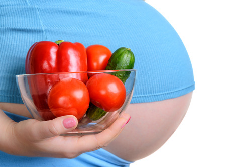 Pregnant woman holding a fresh vegetables, isolated on white backgroundの写真素材