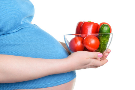 Pregnant woman holding a fresh vegetables, isolated on white backgroundの写真素材