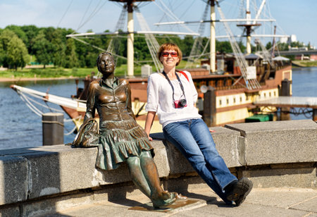 VELIKY NOVGOROD, RUSSIA - JUNE 12, 2014: Female tourist posing next to the sculpture "The girl on the bridge". UNESCO recognised Veliky Novgorod (Novgorod the Great) as a World Heritage Site in 1992.のeditorial素材