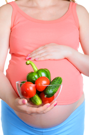 Pregnant woman with fresh vegetables isolated on white backgroundの写真素材