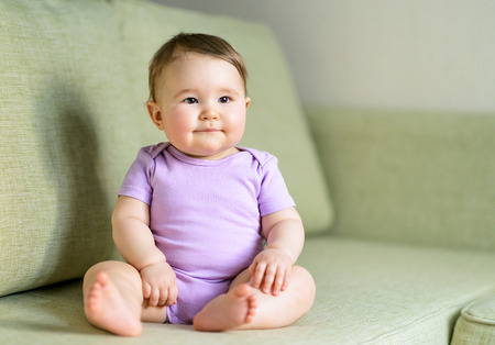 Happy baby sitting on the couch at homeの写真素材