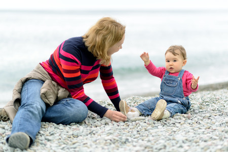 Baby girl playing with her mother on the beachの写真素材