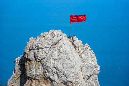 The rock on Mount Ai-Petri with a red flag over Black Sea in Crimea, Russia. Ai-Petri is one of the highest mountains in Crimea and tourist attraction.の写真素材