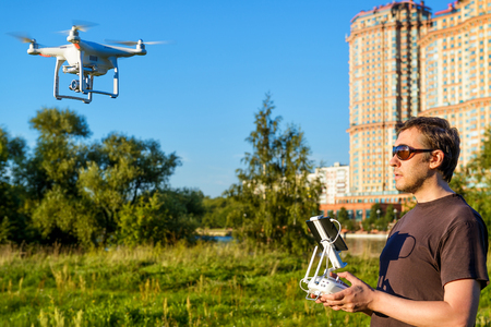 Man operating a drone quad copter with onboard digital camera in the city park