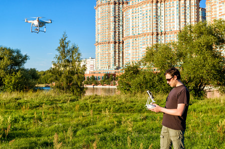 MOSCOW - AUGUST 9, 2016: Man operating a drone quad copter with onboard digital camera in the city...