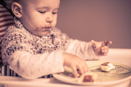 The nice baby with messy face eating cheese cakesの写真素材