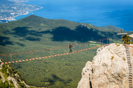 CRIMEA, RUSSIA - MAY 19, 2016: Tourist walking on rope bridge on the Mount Ai-Petri. Ai-Petri is one of the highest mountains in Crimea and tourist attraction.のeditorial素材