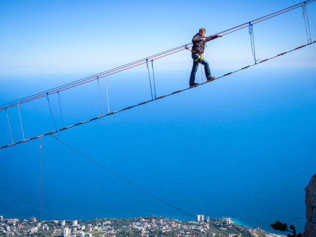 CRIMEA, RUSSIA - MAY 19, 2016: Tourist walking on a rope bridge on the Mount Ai-Petri. It is one of the highest mountains in Crimea and tourist attraction.のeditorial素材