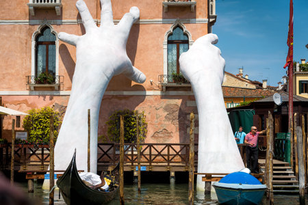 Venice, Italy - May 18, 2017: Giant hands rise from the water of the Grand Canal to support the building. This powerful report on climate change from the artist Lorenzo Quinn.のeditorial素材
