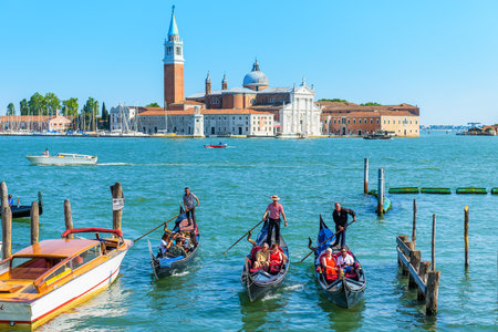 Venice, Italy - May 18, 2017: Gondolas with tourists are sailing along the Venetian lagoon. San Giorgio Maggiore in the background. The gondola is the most attractive tourist transport in Venice.のeditorial素材