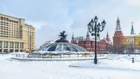 Manezhnaya Square in the winter in Moscow, Russia. Panoramic view of central Moscow during snowfall. Glass cupola crowned by a statue of Saint George, holy patron of Moscow, in the foreground.のeditorial素材