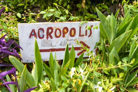 Handmade signpost pointing to the Acropolis in Anafiotika area of Plaka district, Athens, Greece. Plaka and Acropolis are one of the main landmarks of Athens. Vintage sign with an arrow in flowers.の写真素材