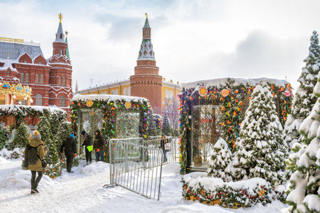 Moscow, Russia - February 5, 2018: People visit the Manezhnaya Square near Moscow Kremlin in winter. Central Moscow with Christmas decorations during snowfall. Historical architecture in old Moscow.のeditorial素材