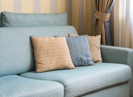 Couch or sofa with cushions in the home interior. Classic couch pillows close-up. Detail of the pastel interior of flat in daylight.