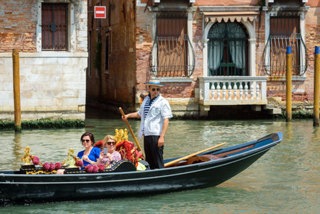 Venice, Italy - May 18, 2017: Gondola sails on the old canal with vintage houses in Venice. Gondola is a most attractive tourist transport of Venice. Romantic water trip across Venice in summer.のeditorial素材