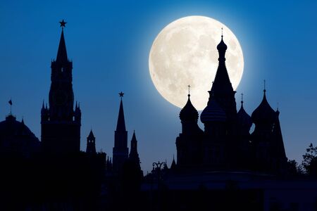 Moscow Kremlin and St Basil`s Cathedral at night, Russia. This place is a top landmark of Moscow. Silhouettes of the famous Moscow symbols against sky with full moon. Moscow city center at dusk.の写真素材