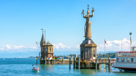 Constance, Germany - July 30, 2019: Old lighthouse and big statue of Imperia in harbor of Konstanz, Germany. Imperia is a landmark of the city. Panoramic view of Constance Lake (Bodensee) in summer.のeditorial素材