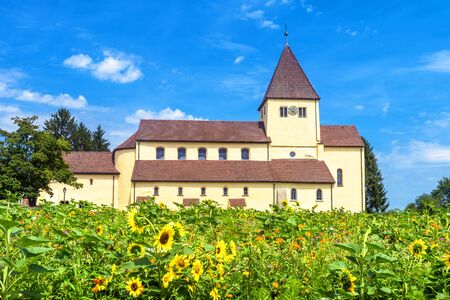 Church of St George in Reichenau Island, Germany. It is a famous tourist attraction of Baden-Wurttemberg. Beautiful scenic view of old Romanesque church beyond flower meadow in summer.の写真素材