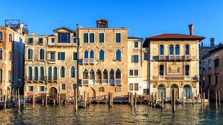 Vintage houses, Venice, Italy. Front view of facades of residential buildings on Grand Canal. Panorama of embankment in the Venice city center in summer. Scenery of old street in Venice on sunny day.の写真素材