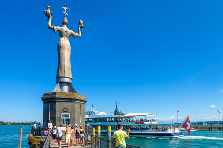 Constance, Germany â July 30, 2019: People visit the statue of Imperia in harbor of Konstanz. It is a famous landmark of city. Big female sculpture at Constance Lake (Bodensee) on blue sky background.のeditorial素材