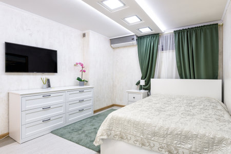 Moscow - Aug 24, 2019: Plain cozy bedroom interior with white design. Modern interior of hotel or home with bed and chest of drawers. Contemporary small bedroom with original lighting.のeditorial素材
