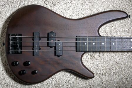 Bass guitar with four strings. Popular rock musical instrument. Top view of brown electric bass on...