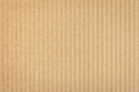 Paper cardboard background. Natural corrugated carton sheet. Kraft cardboard texture with vertical stripes. Seamless light brown paperboard for background or backdrop.の写真素材