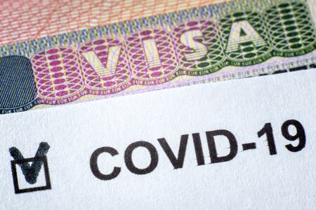 COVID-19 coronavirus pandemic and travel concept, document with COVID positive test and Visa stamp...