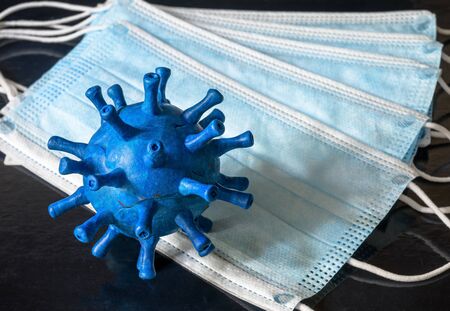 COVID-19 coronavirus or flu concept, model of blue novel SARS-CoV-2 corona virus on medical masks, safety and protection due to coronavirus. Stop spread of global COVID disease pandemic.の写真素材